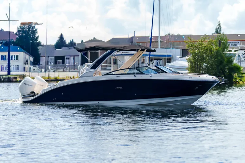 The Image of Luxury Sea Ray boat cruising on a calm waterfront with buildings in the background. - 0