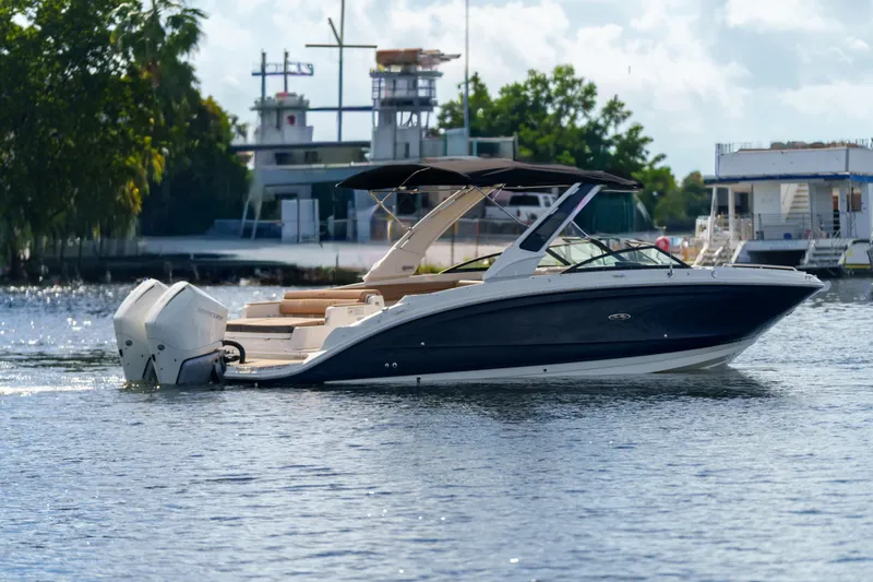 Slide: The Image of Sea Ray boat cruising on a calm river with trees and buildings in the background. - 1