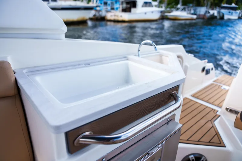 Slide: The Image of Sea Ray boat interior with sink and wooden deck, docked near other boats. - 16