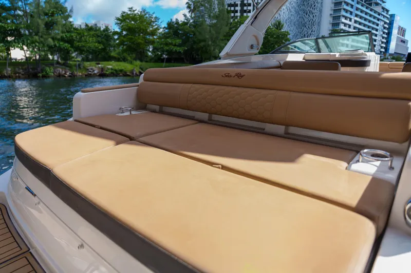 Slide: The Image of Luxurious Sea Ray boat seating with tan cushions, docked near lush greenery and modern buildings. - 23