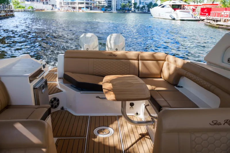 Slide: The Image of Luxurious Sea Ray boat interior with tan seating and wooden table on a sunny waterfront. - 42