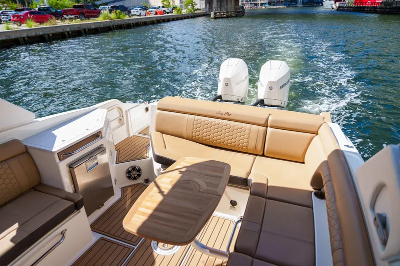 Slide: The Image of Luxury Sea Ray boat interior with tan seating, wooden table, and dual Mercury engines on a sunny day. - 43