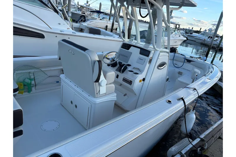 Slide: The Image of 2023 Sailfish 241 CC boat interior at marina, featuring helm and seating. - 6