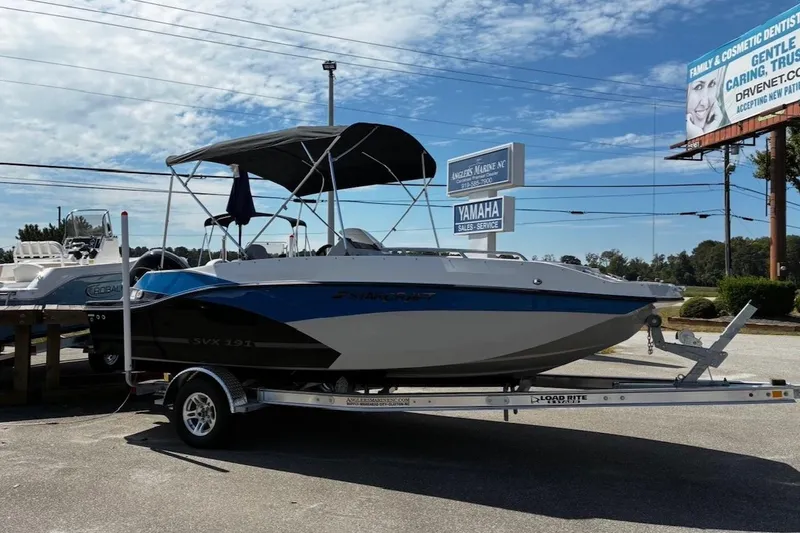 The Image of 2026 Starcraft SVX 191 OB boat on trailer, parked outdoors under a clear sky. - 1
