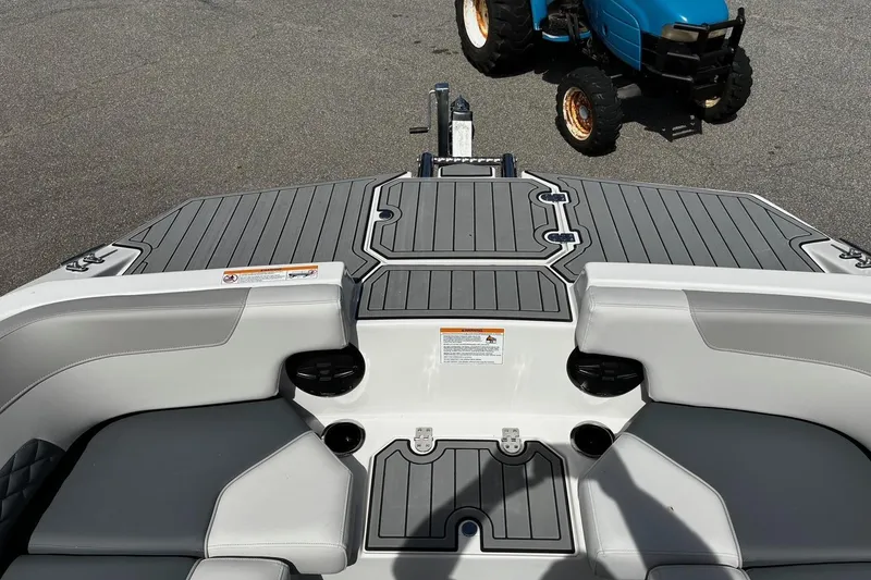 Slide: The Image of 2026 Starcraft SVX 191 OB boat interior with gray seating and deck, parked near a blue tractor. - 14