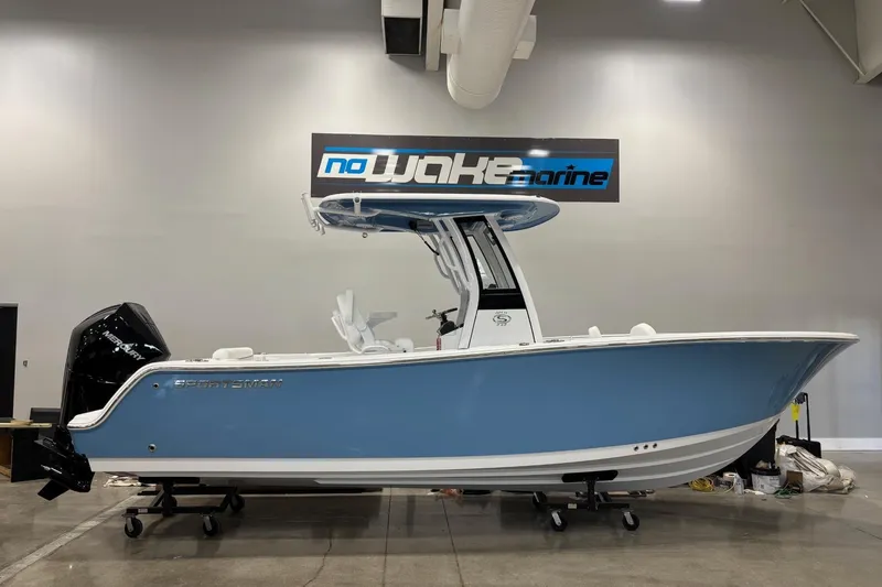 The Image of 2025 Sportsman Open 232 Center Console boat in showroom, blue hull, no wake marine sign. - 0