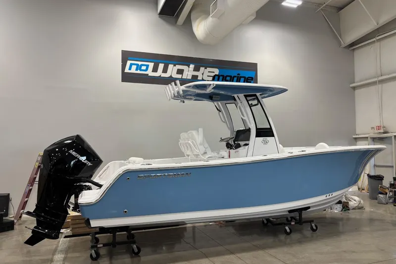 Slide: The Image of 2025 Sportsman Open 232 Center Console boat in showroom, blue hull, powerful outboard motor. - 1