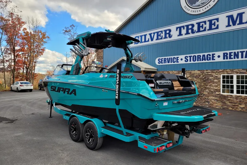 Slide: The Image of 2026 Supra SL boat in vibrant teal, parked outside Silver Tree Marine facility. - 5