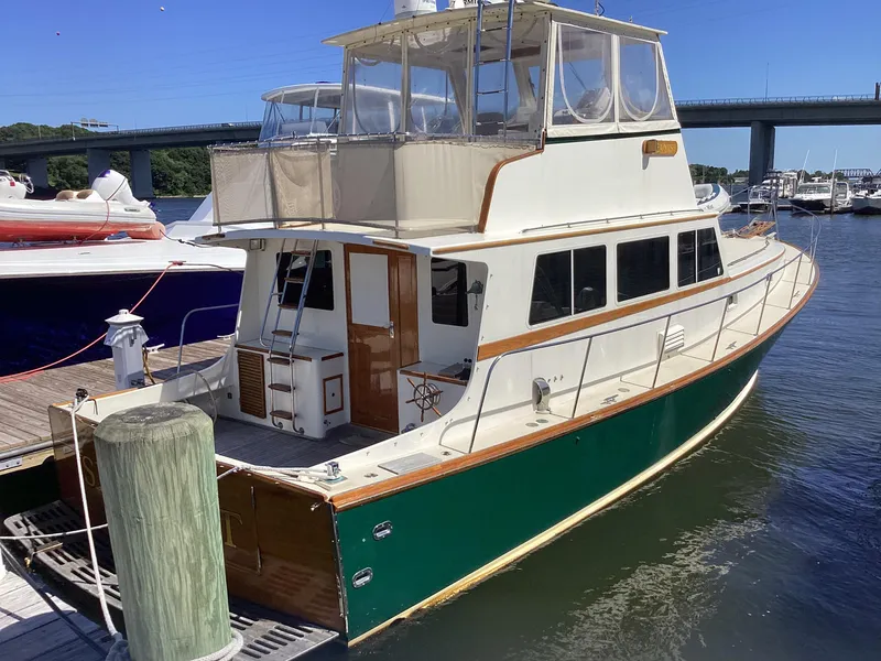 Slide: The Image of 1991 MDI Sedan Flybridge boat docked at marina, featuring green hull and spacious upper deck. - 1