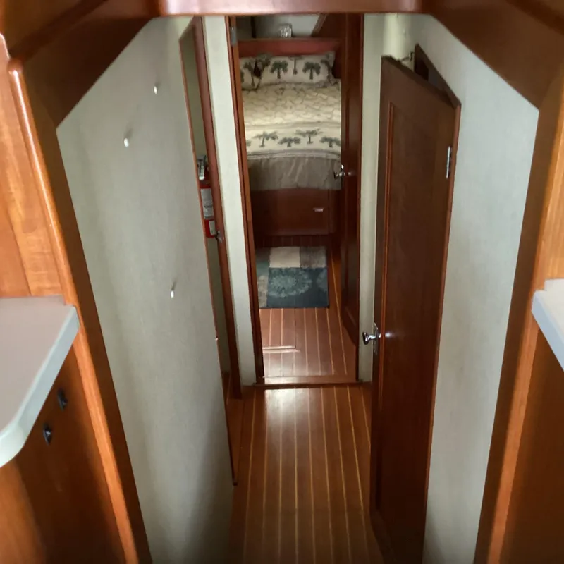 Slide: The Image of Narrow hallway in 1991 MDI Sedan Flybridge with wooden flooring and bedroom view. - 11