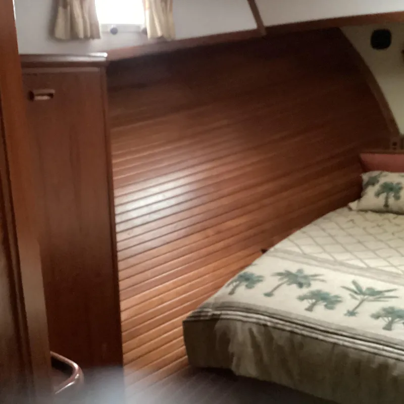 Slide: The Image of Cozy cabin interior of 1991 MDI Sedan Flybridge with wooden paneling and palm-themed bedding. - 20