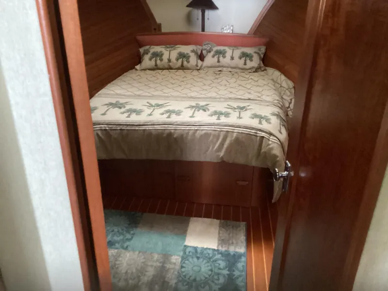 Slide: The Image of Cozy bedroom in 1991 MDI Sedan Flybridge with palm-themed bedding and wooden interior. - 24