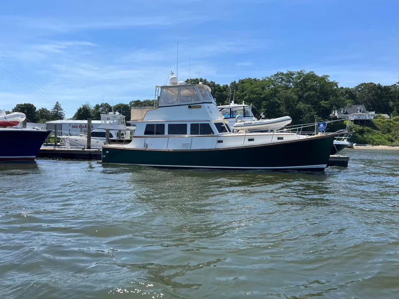 Slide: The Image of 1991 MDI Sedan Flybridge boat docked on a sunny day, surrounded by water and greenery. - 27