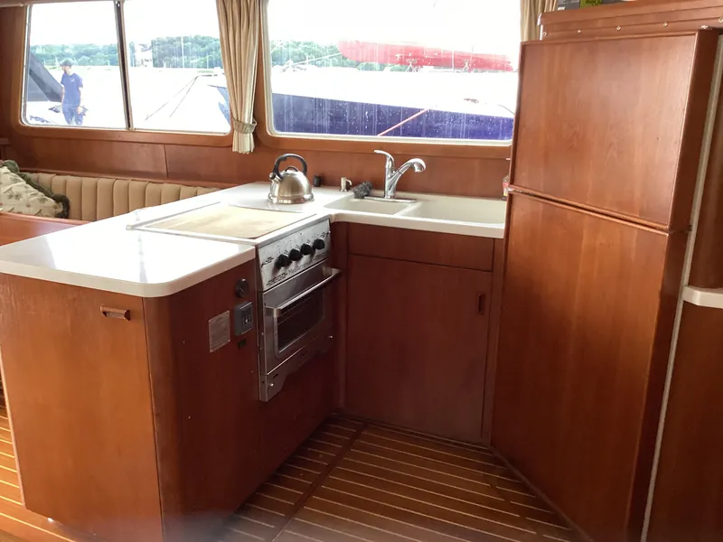 Slide: The Image of 1991 MDI Sedan Flybridge kitchen with stove, sink, and wooden cabinetry. - 6