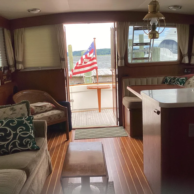 Slide: The Image of Interior of 1991 MDI Sedan Flybridge with American flag, cozy seating, and wooden flooring. - 8