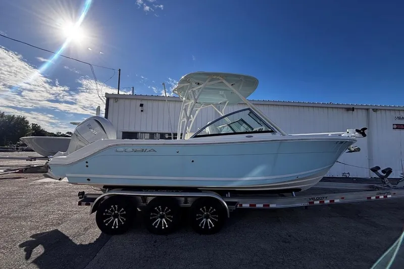 The Image of 2025 Cobia 240 Dual Console boat on trailer under bright sun. - 0