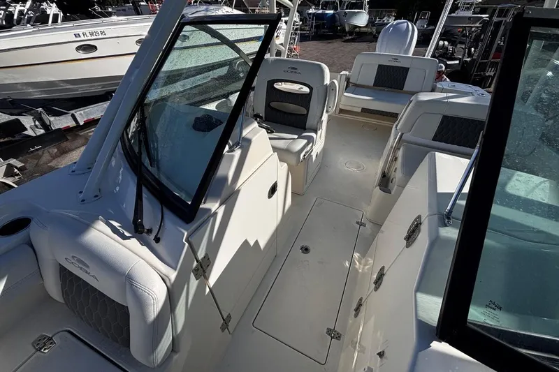 Slide: The Image of 2025 Cobia 240 Dual Console boat interior with seating and windshield, docked at marina. - 16