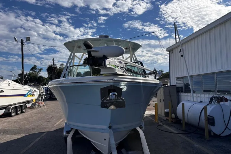 Slide: The Image of 2025 Cobia 240 Dual Console boat docked under a partly cloudy sky. - 2