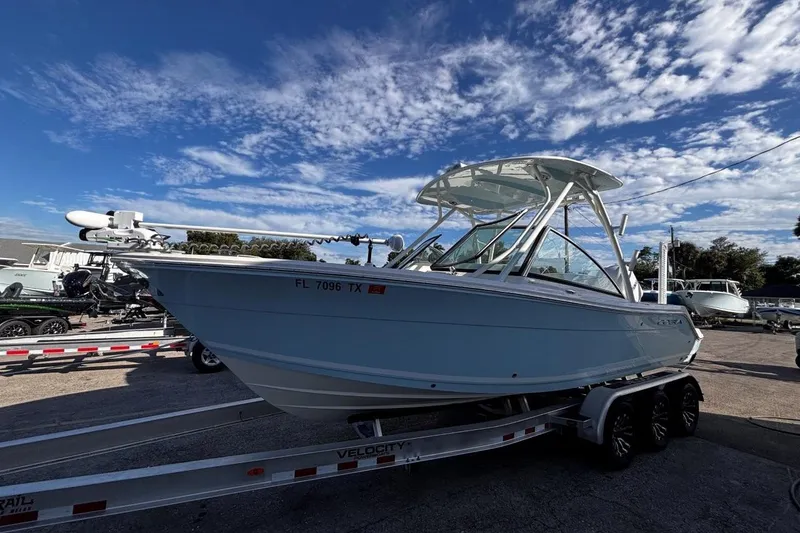 Slide: The Image of 2025 Cobia 240 Dual Console boat on trailer under a clear blue sky. - 3