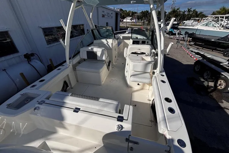 Slide: The Image of 2025 Cobia 240 Dual Console boat interior with seating and storage, docked outdoors. - 8