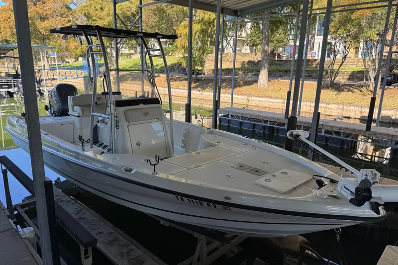 Slide: The Image of 2003 Triton 220 LTS boat docked in a covered marina, surrounded by trees. - 4