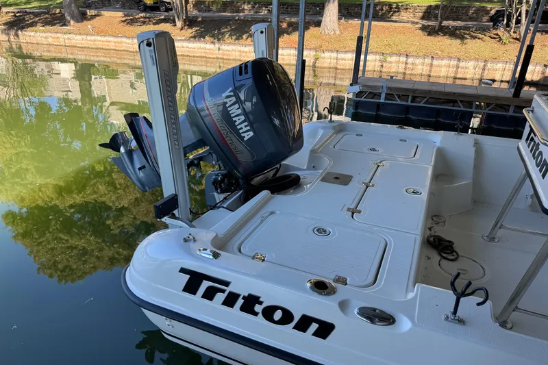 Slide: The Image of 2003 Triton 220 LTS boat with Yamaha outboard motor docked by a calm waterway. - 5