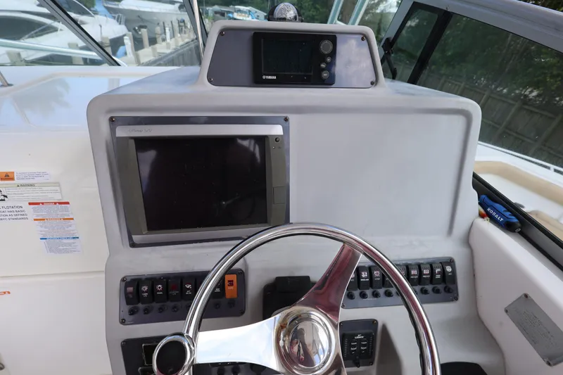 Slide: The Image of 2012 Robalo R305 Walkaround helm with steering wheel and navigation controls. - 13