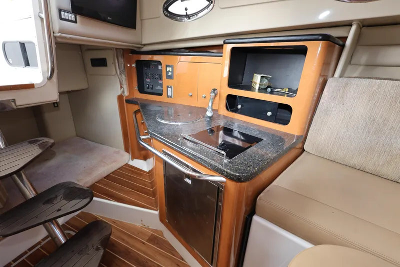 Slide: The Image of 2012 Robalo R305 Walkaround cabin interior with kitchenette and seating area. - 17