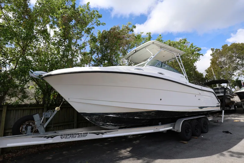 Slide: The Image of 2012 Robalo R305 Walkaround boat on trailer, surrounded by trees and blue sky. - 25
