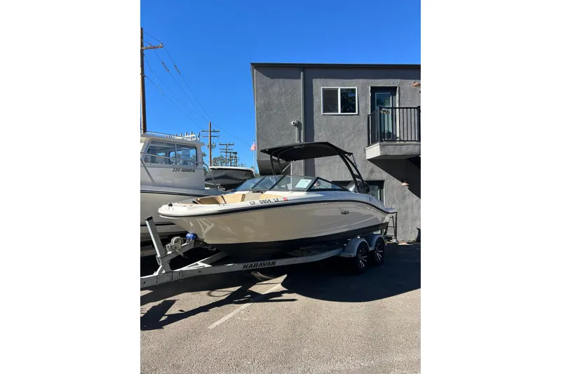 Slide: The Image of 2023 Sea Ray SPX 190 Outboard boat on trailer, parked outdoors under clear blue sky. - 0