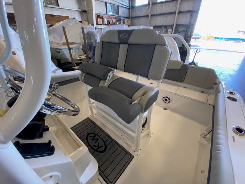 Slide: The Image of 2026 Key West 219 FS boat interior with cushioned seating and steering wheel in a showroom. - 8