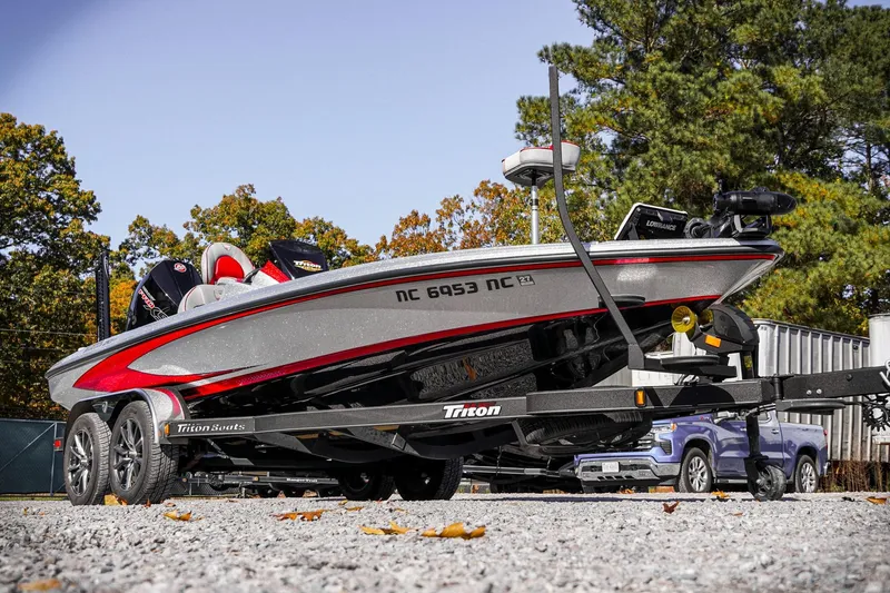 Slide: The Image of 2024 Triton 20XP boat on trailer, parked outdoors with trees in background. - 41