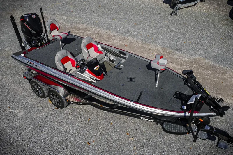 Slide: The Image of 2024 Triton 20XP fishing boat with dual seats and motor, parked on gravel. - 8
