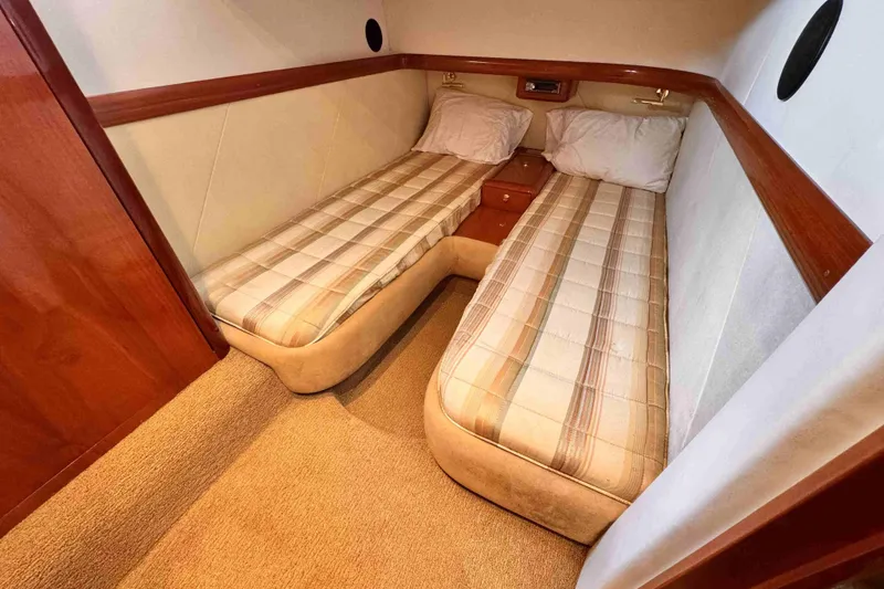 Slide: The Image of Twin beds in a Cranchi yacht cabin with plaid bedding and wooden accents. - 14