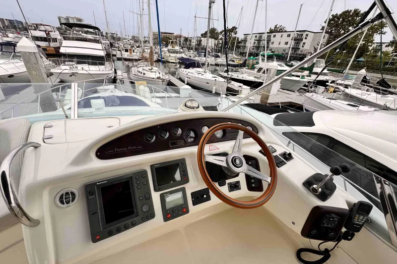 Slide: The Image of Cranchi yacht helm with wooden steering wheel, docked in a marina with multiple boats. - 2
