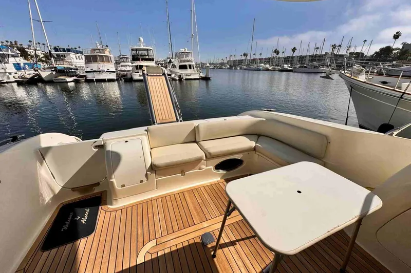 Slide: The Image of 2003 Cranchi Atlantique 50 yacht deck with seating and table, docked in a marina. - 8