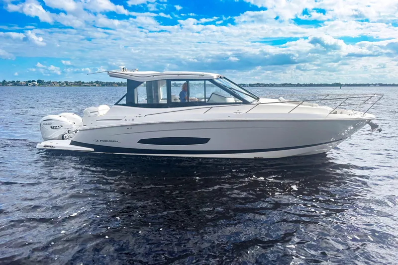 The Image of 2024 Regal 36 XO boat cruising on a sunny day with clear blue skies. - 0