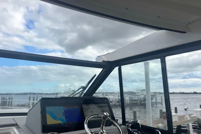 Slide: The Image of 2024 Regal 36 XO boat helm with navigation display, overlooking marina and cloudy sky. - 15