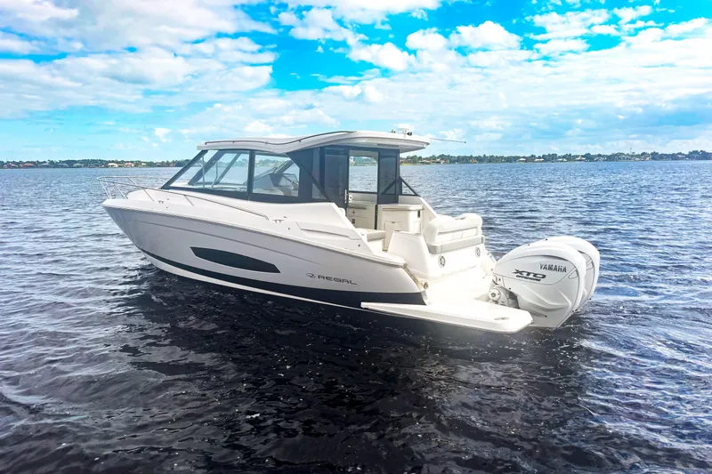 Slide: The Image of 2024 Regal 36 XO boat on water with Yamaha outboard engine, under a blue sky. - 2