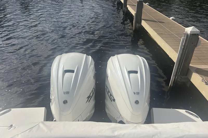 Slide: The Image of Twin V8 outboard engines on a 2024 Regal 36 XO boat docked by a pier. - 26