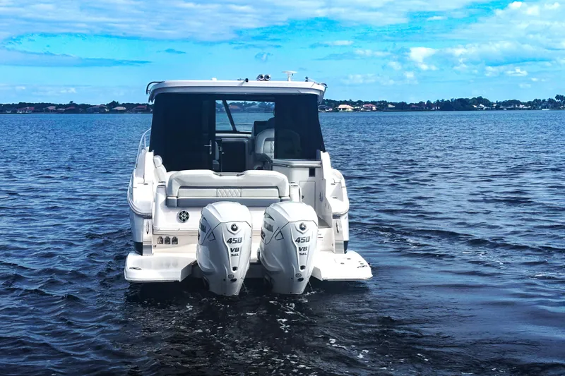 Slide: The Image of 2024 Regal 36 XO boat with dual outboard engines on a calm lake. - 3