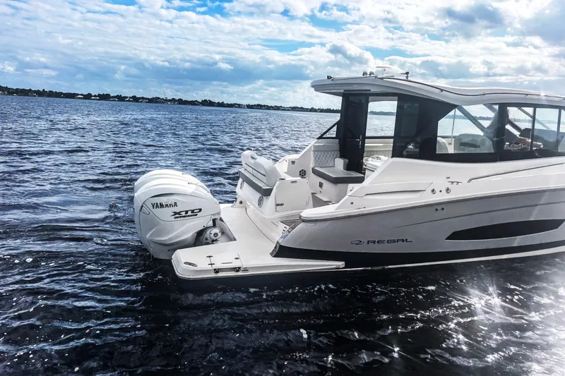 Slide: The Image of 2024 Regal 36 XO boat cruising on open water under a partly cloudy sky. - 5