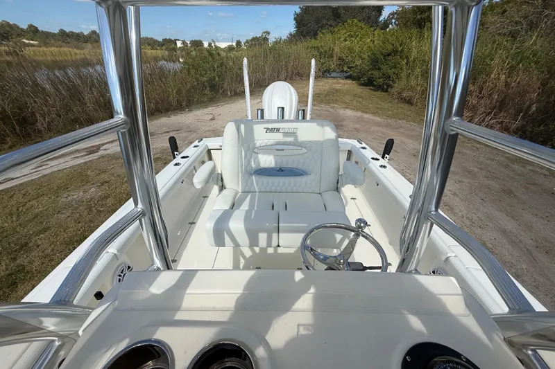 Slide: The Image of 2026 Pathfinder 2400 Open boat interior with steering wheel and seating, parked on grassy terrain. - 26