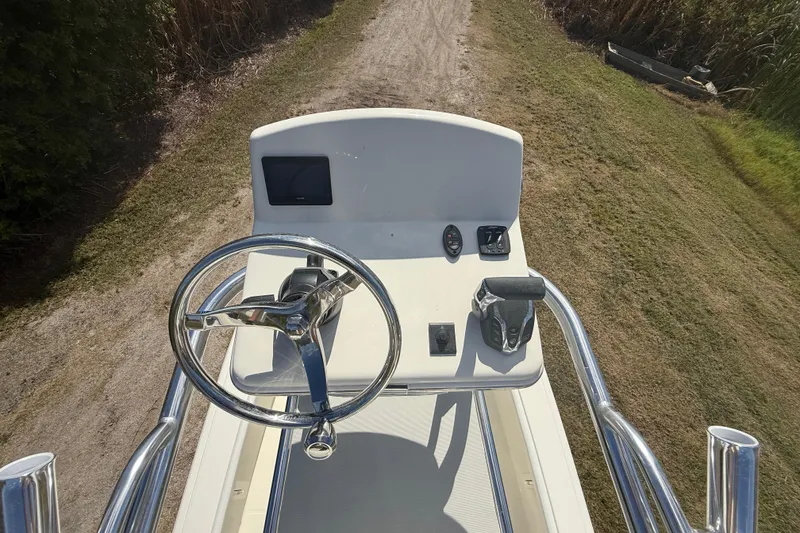 Slide: The Image of 2026 Pathfinder 2400 Open boat console with steering wheel and controls on a grassy path. - 50
