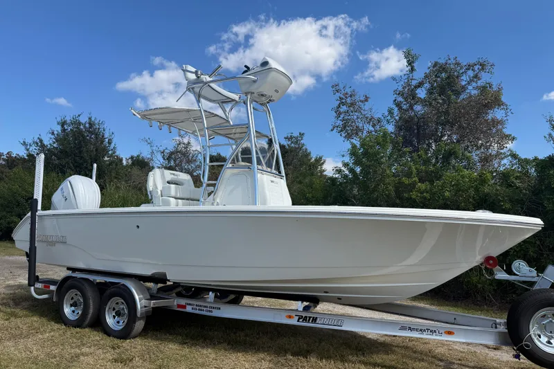 Slide: The Image of 2026 Pathfinder 2400 Open boat on trailer, set against a clear sky and greenery. - 9