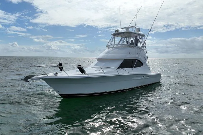 Slide: The Image of 2005 Riviera 40 Flybridge yacht on open water under a partly cloudy sky. - 4
