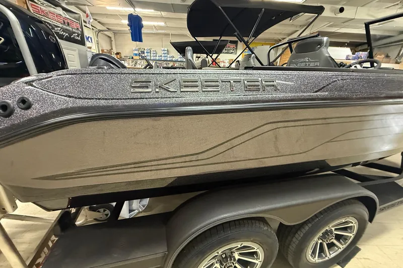 Slide: The Image of 2026 Skeeter WX1910 boat in showroom, metallic finish, on a trailer. - 1
