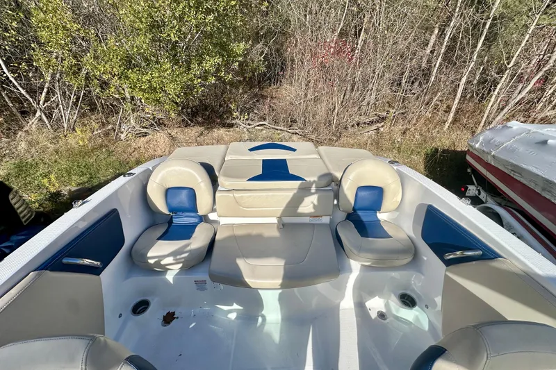 Slide: The Image of 2018 Chaparral 19 H2O Ski & Fish boat interior with seating, surrounded by trees. - 11