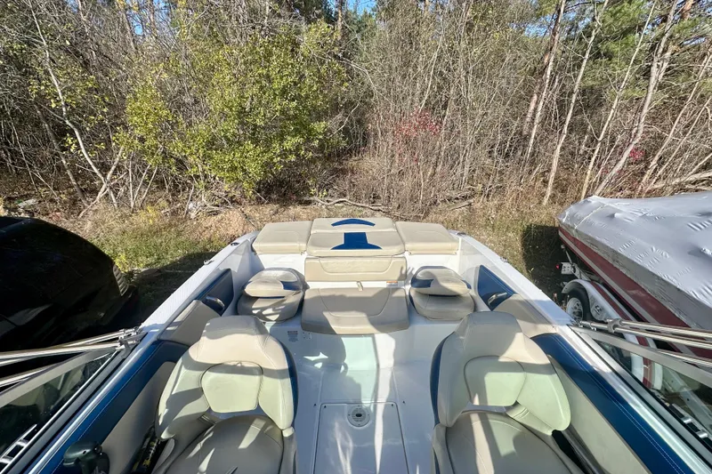 Slide: The Image of 2018 Chaparral 19 H2O Ski & Fish boat interior with seating, surrounded by trees. - 7