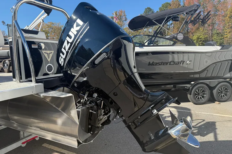 Slide: The Image of 2026 Tahoe Pontoon Cascade Quad Lounger with Suzuki outboard motor, parked beside MasterCraft boat. - 12